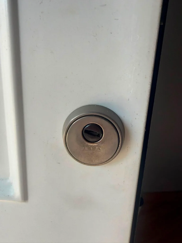 Escudo de seguridad redondo TESA instalado en una puerta blanca