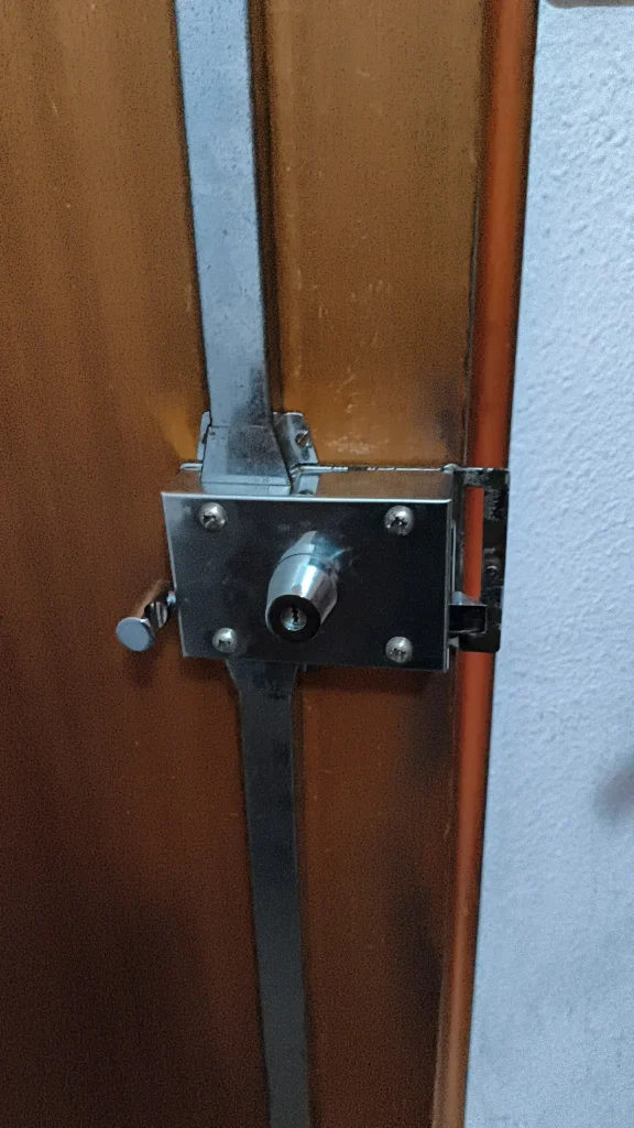 Cerradura de sobreponer con cerrojo vertical en una puerta metálica